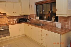 莫希尔Woodside Self Catering Lough Rynn的厨房配有白色橱柜和水槽