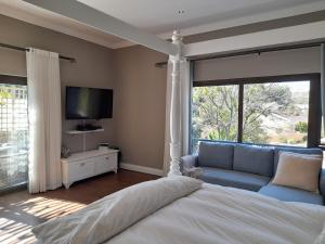 温特和克Safari Villa Botique Hotel的一间卧室配有一张床、一台电视和一张沙发