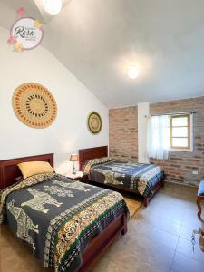 Hacienda ZuletaSanta Rosa de Lima Hostal Zuleta的一间卧室设有两张床和砖墙