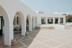 塔格梅斯Hotel Bougainvillier Djerba的白色建筑的庭院,配有桌椅