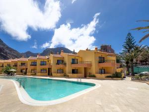 巴耶格兰雷伊三棵棕榈树度假酒店的一座带游泳池的度假村,位于一座建筑前