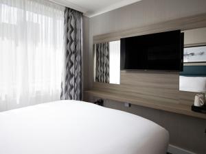 伦敦City Sleeper at Royal National Hotel的一间卧室配有一张床和一台平面电视