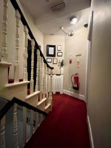 伦敦Trinity House Hotel的铺有红地毯的走廊和铺有红色地板的楼梯
