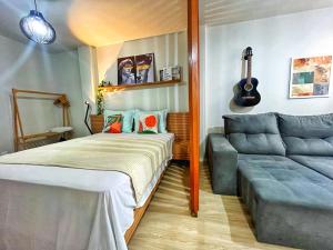 马卡埃LOFT aconchegante no Centro de Macaé, Wifi, Ar condicionado e Cozinha completa的一间卧室配有一张床、一张沙发和吉他