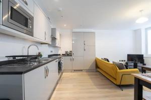 Central Gloucester Getaway Retreat W/Free Parking的厨房配有白色橱柜和黄色沙发