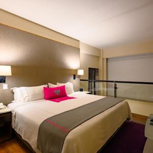 墨西哥城坎波斯艾里西欧司套房酒店的一间卧室配有一张带粉红色枕头的大床