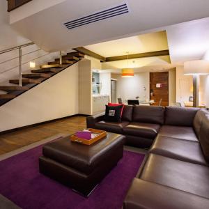 墨西哥城坎波斯艾里西欧司套房酒店的客厅设有真皮沙发和楼梯。