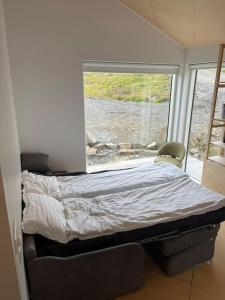 ReynivellirPeaceful Lakeside Cabin的卧室在窗户前配有一张床