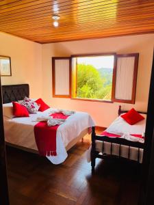 坎波斯杜若尔当Casa Bela vista的一间卧室配有两张带红色枕头的床和窗户。