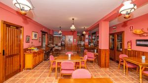 特雷韦莱斯拉伏拉加II酒店的餐厅拥有粉红色的墙壁和木桌及椅子