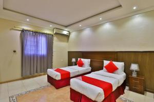 延布فندق نجمة سماء ينبع البحر的两张位于酒店客房的床,配有红色和白色枕头