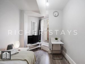伦敦Hackney Guest Rooms的白色的卧室设有床铺和墙上的电视