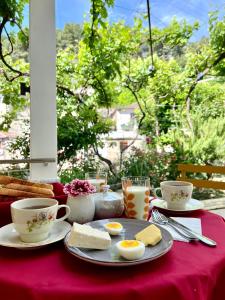 培拉特Nika's Guest House的一张桌子,上面放着一盘鸡蛋,面包和杯子