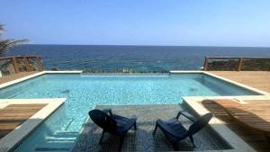 西湾Casa Flomingo Roatan的一个带两把椅子的游泳池以及大海