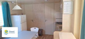 维亚雷焦Mobile home Viareggio - Camping Paradiso- Including airco -Zona Gialla 016的一间带桌子和冰箱的小厨房