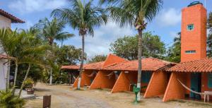 因巴塞Pousada Tupi Imbassai的一座种植了棕榈树的橙色建筑
