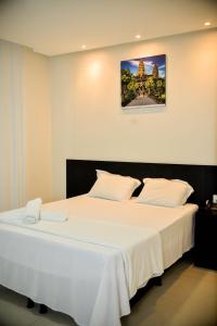 阿拉皮拉卡hotel quatro coracoes的卧室配有一张白色大床,墙上挂着一幅画