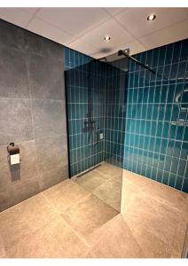 韦默尔丁厄Hotel Brasserie Smits的带淋浴的浴室和蓝色瓷砖墙