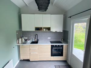 哈伦Blokhut Klein Meerzicht的厨房配有白色橱柜、水槽和窗户。