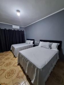 瓜鲁柳斯Villa Fátima Hostel GRU的蓝色墙壁客房的两张床