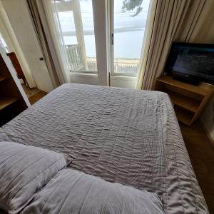 皮奇勒姆Max & Mar Pichilemu的一间卧室配有一张床、一台电视和一个窗口