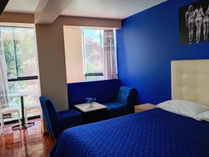 库斯科Munay Wasi CUSCO的蓝色卧室设有床、椅子和窗户