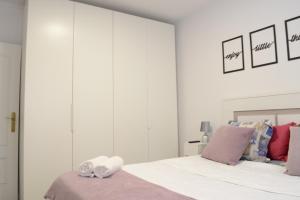 马德里Bonito Apartamento Madrid Rio的白色卧室配有带紫色枕头的床