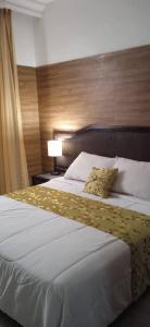 MacutoHotel Eduards Suite的卧室配有一张白色大床和木制床头板