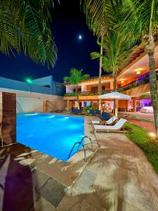 瓜鲁雅Luna Hotel Boutique - Beira Mar的棕榈树的夜间度假村游泳池