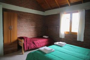 普埃洛湖Chacra confluenza的一间卧室设有两张单人床和砖墙