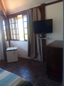 因巴塞Pousada Tupi Imbassai的一间卧室配有一张床和一台平面电视