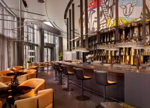 伦敦art'otel London Hoxton的餐厅内的酒吧,配有椅子和葡萄酒瓶