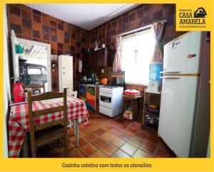 布卢梅瑙Casa Amarela Blumenau Hospedagem Alternativa的厨房配有桌子和白色冰箱。