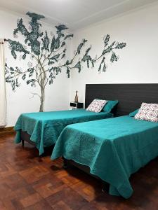 卢汉德库约JURAMA的卧室配有两张床,墙上有一棵树