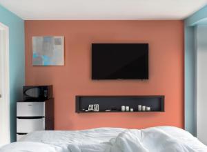 South Hadley格兰比汽车旅馆的一间卧室设有带平面电视的橙色墙壁