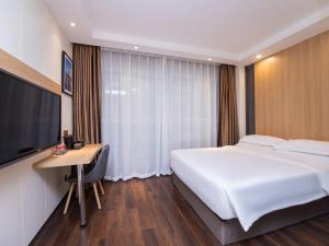 上海丽怡酒店·上海浦东机场川沙地铁站店的一间卧室配有一张床、一张书桌和一台电视