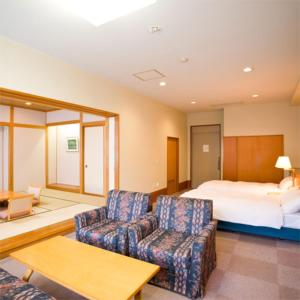 长野Asoviva Nagano Park的一间卧室配有一张床、两把椅子和一张桌子