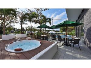 名户Green Rich Hotel Okinawa Nago - Vacation STAY 49879v的甲板上的热水浴池配有桌椅
