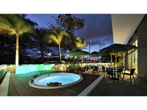 名户Green Rich Hotel Okinawa Nago - Vacation STAY 49879v的甲板上的热水浴池配有桌子和遮阳伞