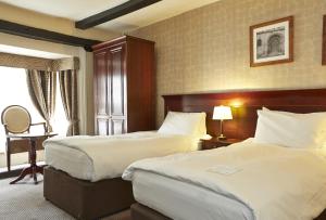 亨廷登George Hotel by Greene King Inns的酒店客房设有两张床和窗户。