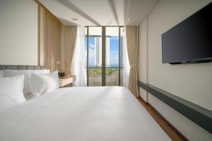 岘港Tashi Ocean Hotel & Apartment Da Nang的一间卧室配有一张大床和一台平面电视
