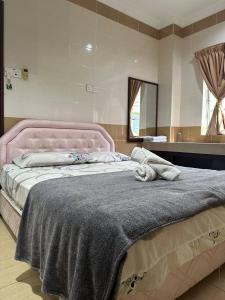 而连突绿叶悦椿家庭酒店的卧室内的一张带粉红色床头板的大床