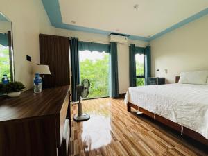 峰牙Phong Nha Moonlight Villas的一间卧室配有一张床和一张带风扇的书桌