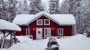 罗瓦涅米Kotatuli Forest Lodge的屋顶上积雪的红色房子