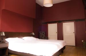BredevoortHotel Bertram的卧室设有白色的床和红色的墙壁