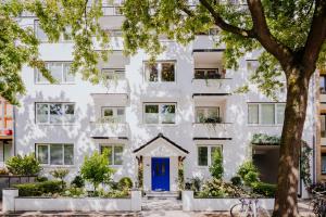 汉堡Apartmenthaus Hamburg Les Jardins的白色的公寓楼,设有蓝色的门