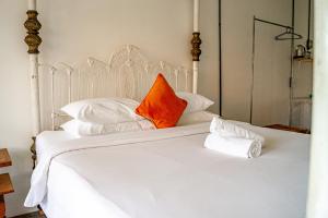 坎古Sepeda Hostel的白色的床,配有橙色枕头和白色枕头
