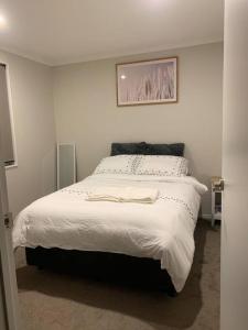 奥克兰Serene 5-Bedroom Papakura Home的卧室配有一张白色床,墙上挂着一幅画