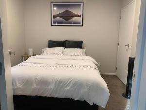 奥克兰Serene 5-Bedroom Papakura Home的卧室配有一张白色床,墙上挂着一幅画