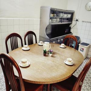 蕉赖Cheras Landed Homestay 4BR - 10Pax - MRT Suntex的厨房里的木桌,配有杯子和碟子